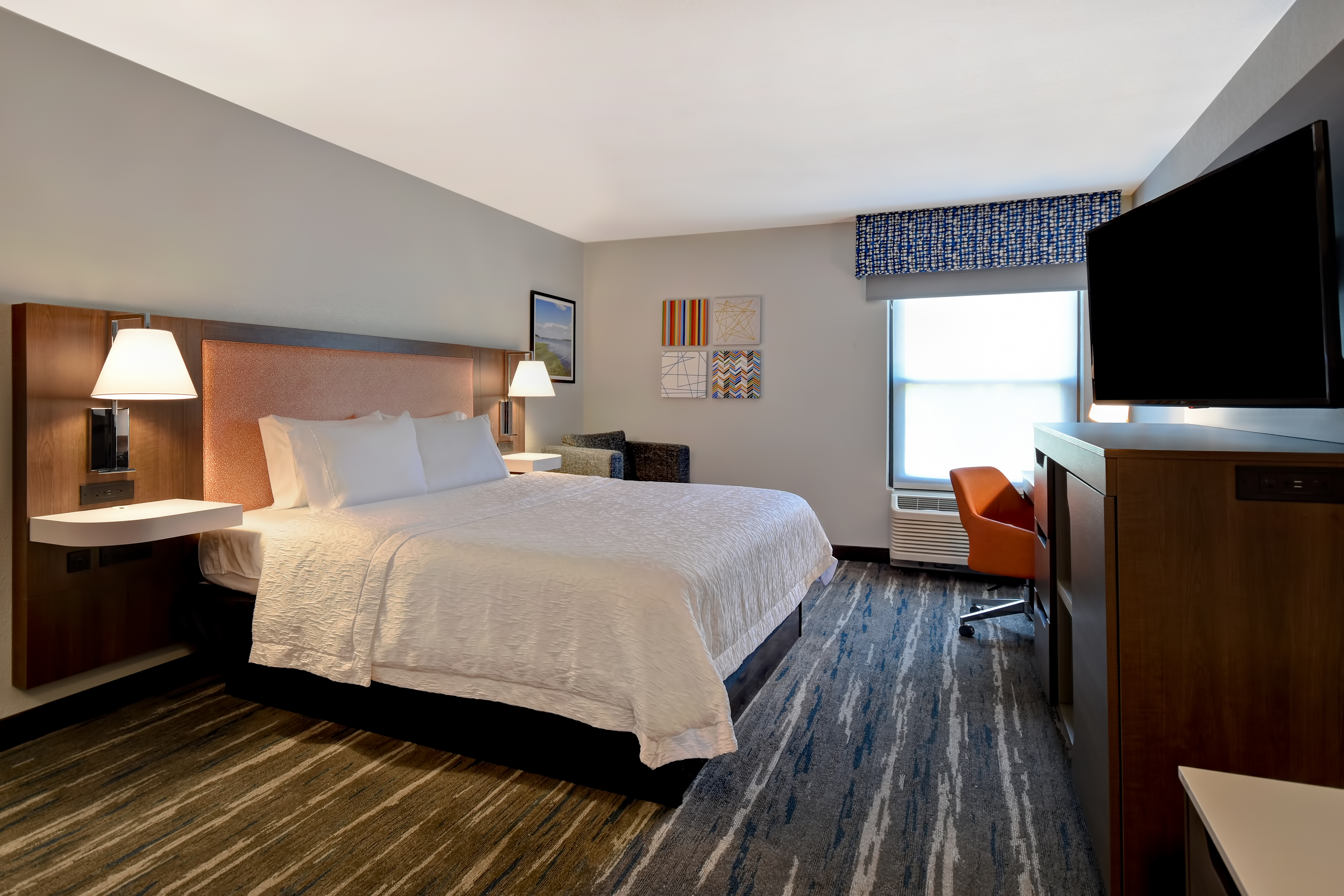 a guest room with bed television lounge chair and window