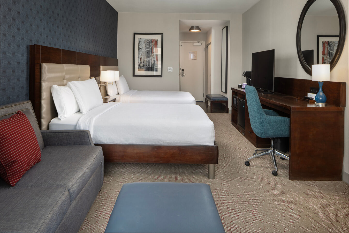 Sofa, Two Beds, TV and Desk with Mirror in a Guest Room