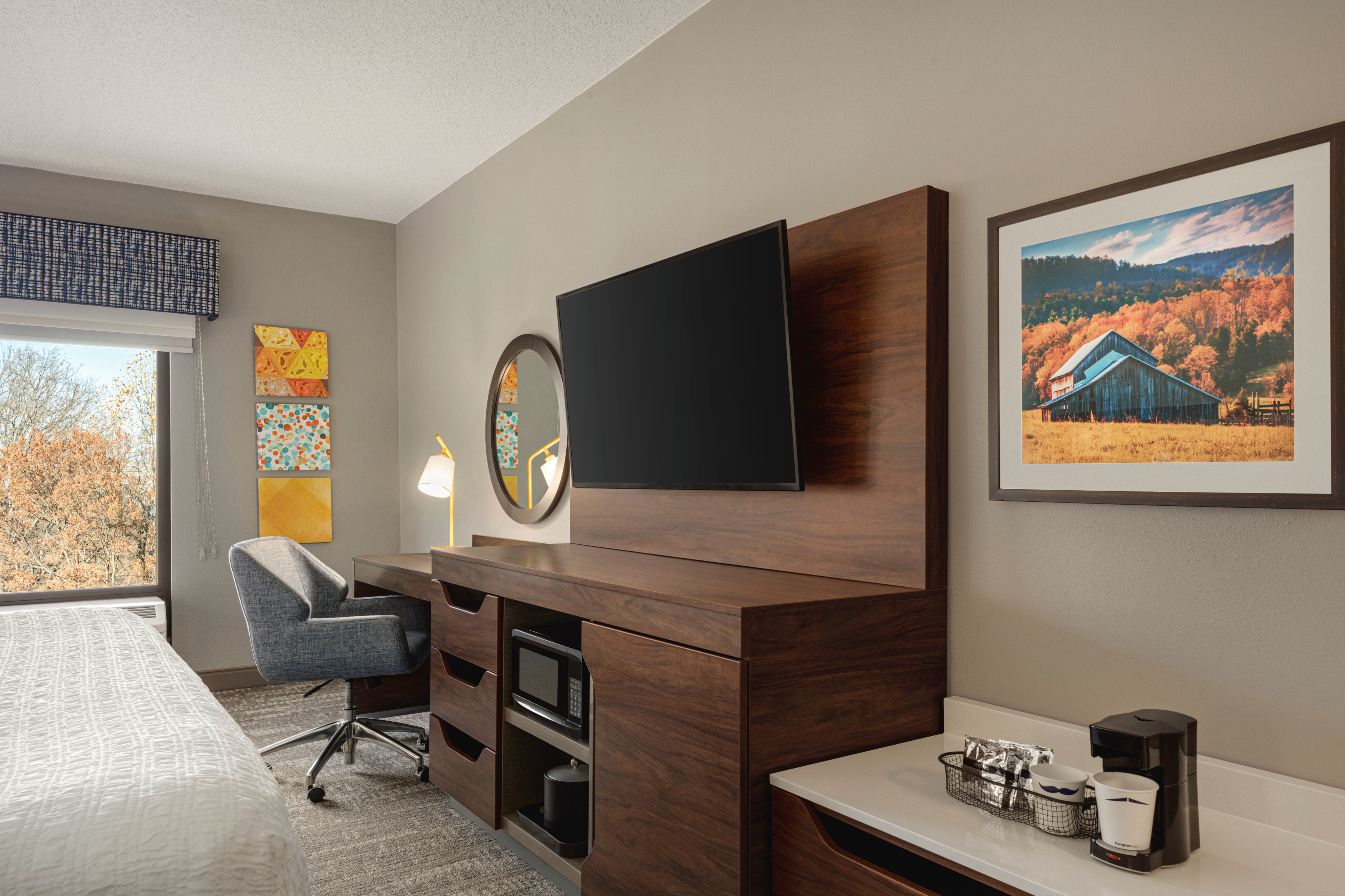 King guest room with a TV, work desk and window view 