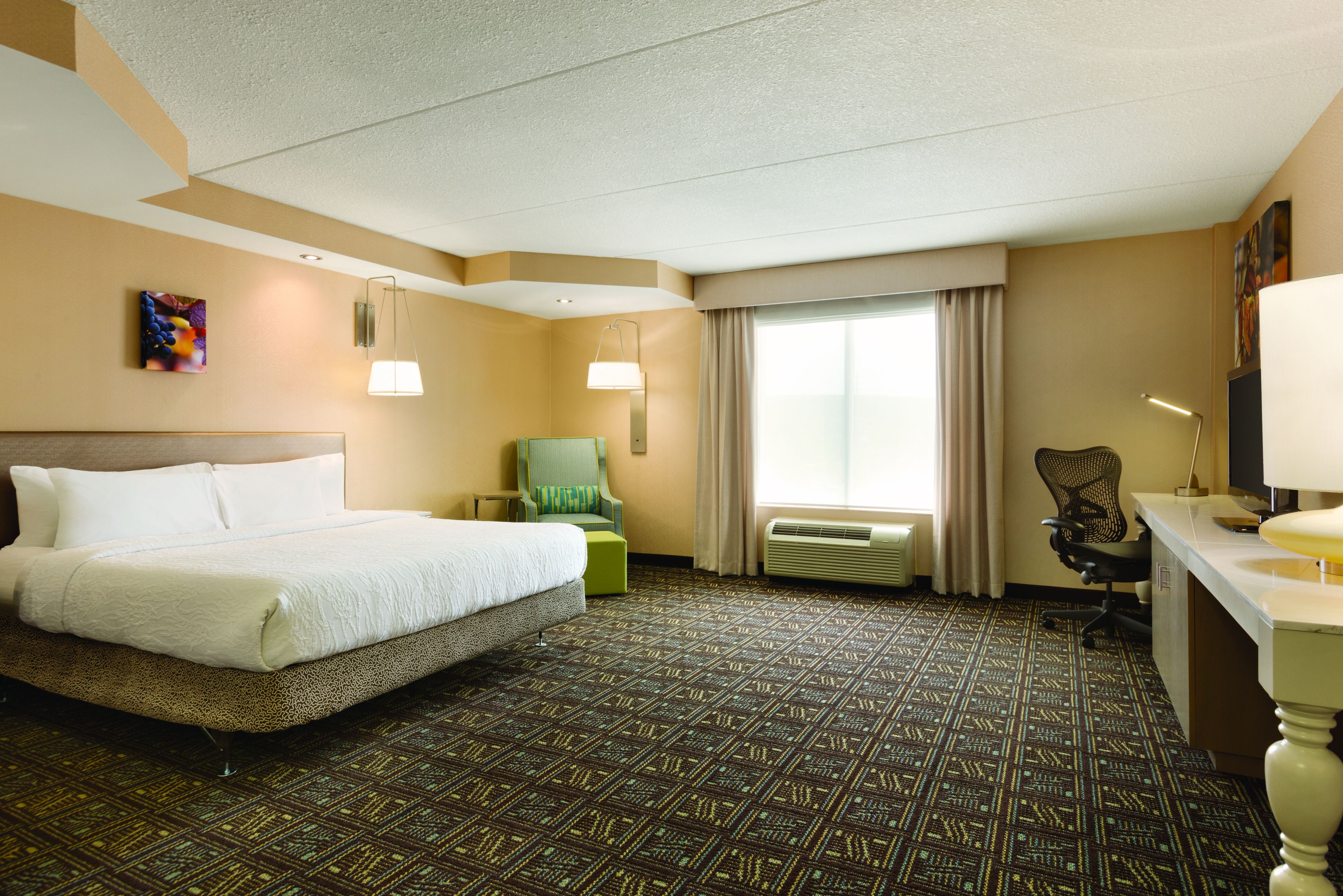 King Bed, Illuminated Lamps, Armchair, Window With Long Drapes, Work Desk, and TV in Accessible Guest Room
